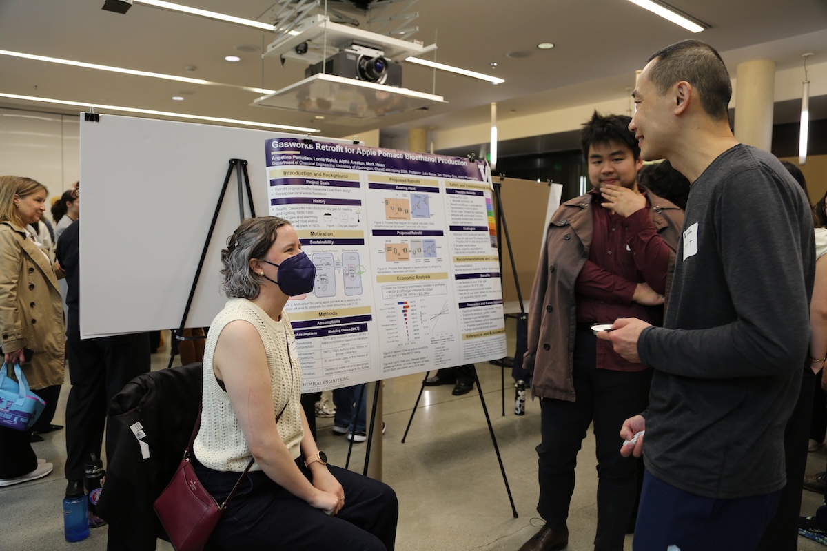 Students from the winning team "Team Apple ^ 4" explain their research to a guest.