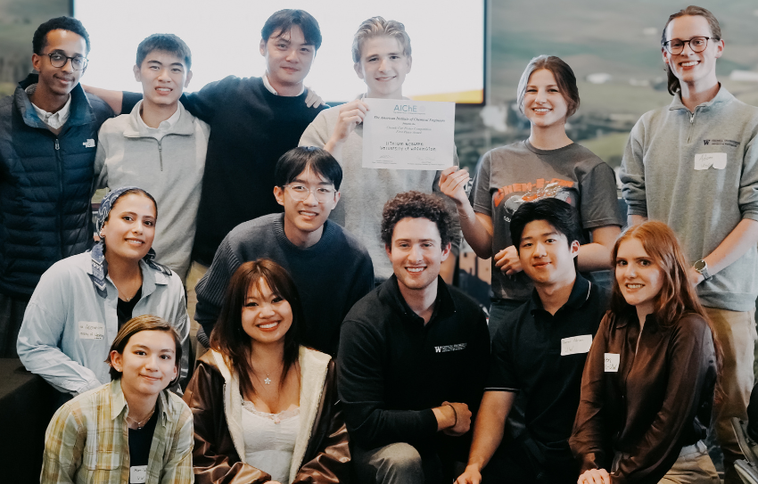 A large group of students hold up a certificate for first place and smile at the camera.