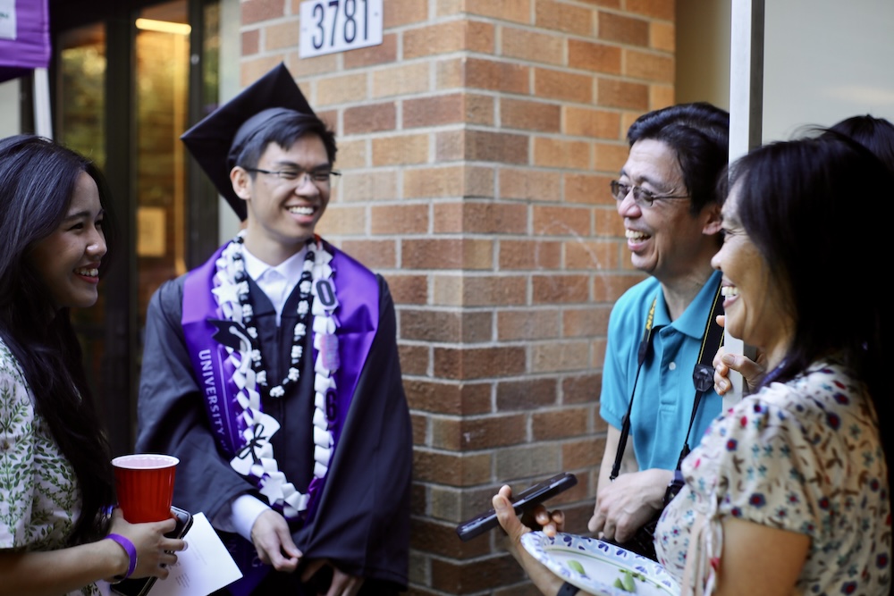 An undergraduate student talks with family and friends at a reception.