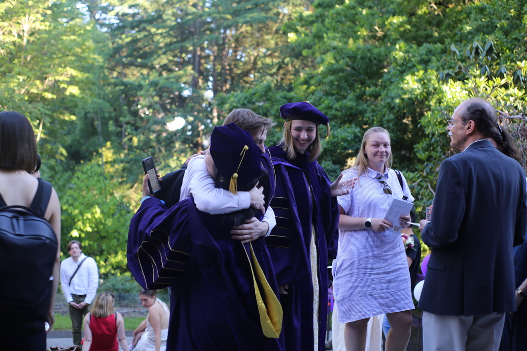 Recent Ph.D> graduates hug at the commencement reception.