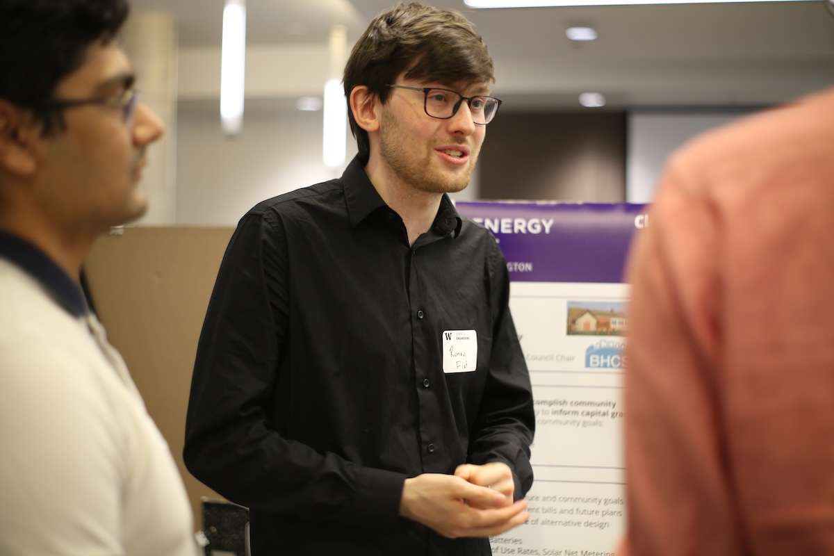 Students talk to a guest in front of their poster at the reception. 