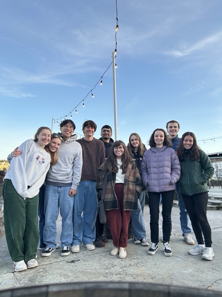 A small group of people stand outside on a sunny day. 
