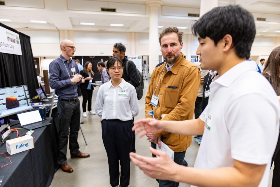A group of students standing next to a table, explaining their project