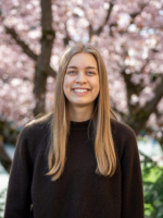 Sofia Dahlgren smiling while standing in front of blooming cherry blossoms.