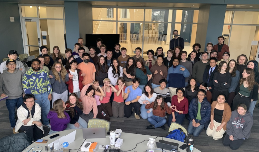 A large group of people sitting in a classroom making silly faces. 