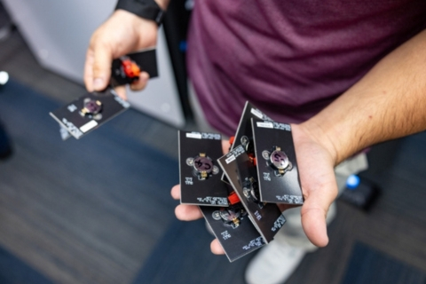 A researcher holds a collection of small silver coin cell batteries in at the Clean Energy Testbeds