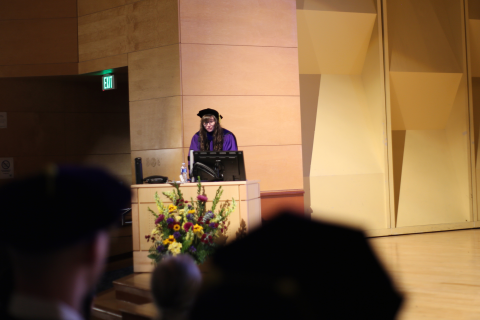 Alex Prybutok stands at the podium and gives a speech during graduation.