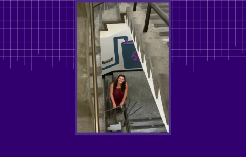 Naudia Watkins standing in the stairwell with her mural, looking up at the camera. 