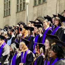 Undergraduate students in their caps and gowns pose for a class photo at graduation.