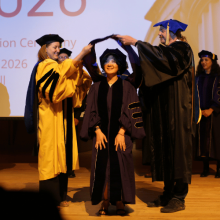 A student receives their doctoral hood during graduation.